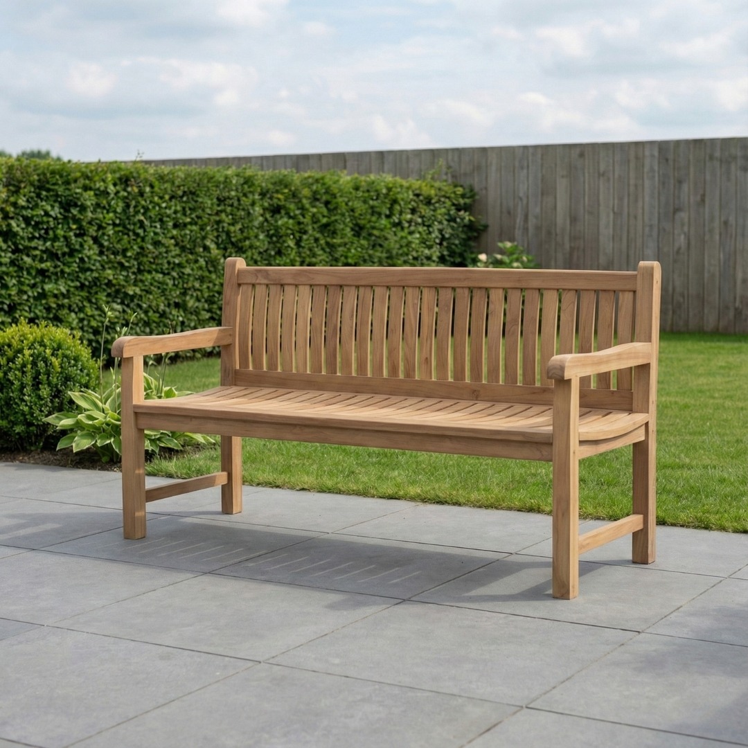Rechte teakhouten tuinbank met verticale spijlenrug voor een bakstenen muur en kleurrijke hortensia struiken. - alternate view
