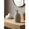 Natuurstenen zeepdispenser met rvs pomp op eikenhouten badkamermeubel in een minimalistische, moderne badkamer setting.