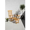Verstelbare teakhouten deckchair met voetensteun naast inklapbare houten bijzettafel op zonnig terras met olijfboom.