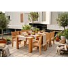 Een sfeervolle foto van een grote, rechthoekige teakhouten tuintafel met zes bijpassende teakhouten stoelen op een zonnig, betegeld terras. De tafel is stijlvol gedekt met linnen lopers, servies, houten schalen met fruit en brood, en kruidenplanten. De st