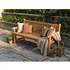 Sfeervolle houten tuinbank op een zonnig terras, aangekleed met kussens in aardetinten, een gebreid plaid, terracotta potten en een houten lantaarn