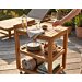 Trolley - Teakea Luxe teakhouten serveerwagen op een zonnig terras, gestyled als buitenbar met wijn en hapjes. Een hand pakt een wijnglas van het bovenblad.