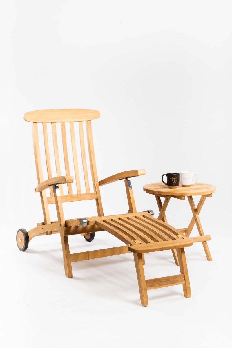 Verstelbare teakhouten deckchair met voetensteun naast inklapbare houten bijzettafel op zonnig terras met olijfboom. - alternate view