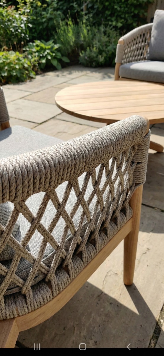 driedelige teakhouten tuinset, bestaande uit twee loungestoelen met een open, grijs gemêleerd rope vlechtwerk en grijze kussens, plus een bijpassende ronde houten salontafel, tegen een neutrale witte achtergrond - view 3